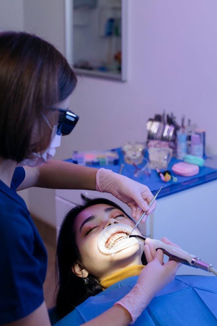 gallery-6 Dentist examining patient's teeth with tools in a modern clinic setting.